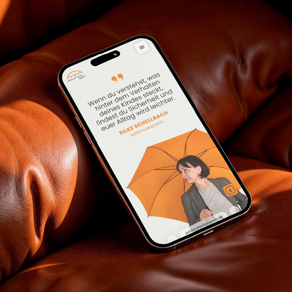 Ein Smartphone liegt auf einem Ledersofa und zeigt die Website autismusfamilysupport.